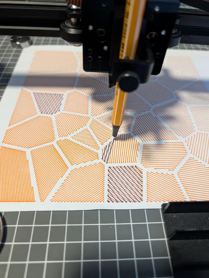 Der Plotter zeichnet orange schraffierte Voronoi-Zellen auf weißes Papier; ein zweiter, blauer Stift setzt gerade die Schraffur einer einzelnen Zelle.